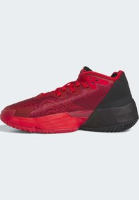 Zapatilla deportiva roja con parte superior de malla texturizada, talón negro contrastante y suela de goma con un patrón único y puntera reforzada.