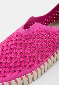 Scarpa slip-on rosa con tomaia testurizzata e perforata caratterizzata da motivi a scallop. Design a punta chiusa con suola in gomma beige e dettagli cuciti.