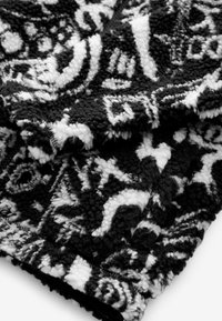 Mustvalge plush tekk, millel on tekstuuriline, mustriline disain keerdus kujunditega ja luksuslik pehme kangas.
