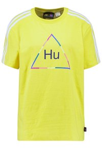 Gul bomullströja med korta ärmar, har en triangulär grafik med "Hu"-text och tre vita ränder på varje axel.