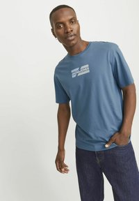 Blå bomulds t-shirt med hvid logo-print, korte ærmer og klassisk rund hals, parret med mørke denim jeans.