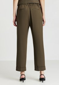 Pantaloni verdi oliva con una vestibilità ampia, vita elastica e orli a ribasso, dotati di due tasche posteriori e una texture liscia.