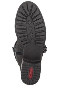 Bottine noire avec semelle en caoutchouc texturé présentant un motif de tread, fermeture éclair sur le côté et surpiqûres décoratives le long du bord supérieur.