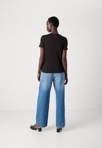 Svart kortermet t-skjorte kombinert med lyseblå vide jeans. Antrekket har en avslappet passform og myk, glatt stoff.