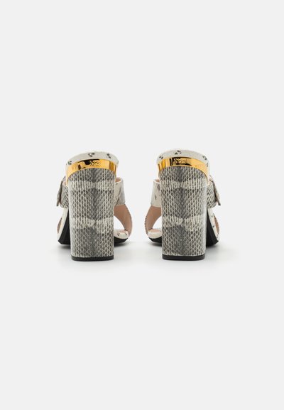 Sandales à talons hauts avec un motif serpent en gris et blanc, accentuées d'une touche dorée sur le talon. Design à l'arrière et sur les côtés ouverts.