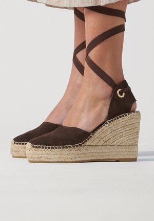 Sandali espadrillas con zeppa con tomaia in suede marrone scuro e cinturini che avvolgono la caviglia su suole platform in corda di juta intrecciata.