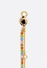 Pulsera de cadena de oro con brillantes de colores en diversas formas y tonalidades, con un charm circular decorado con un diseño de corazón.