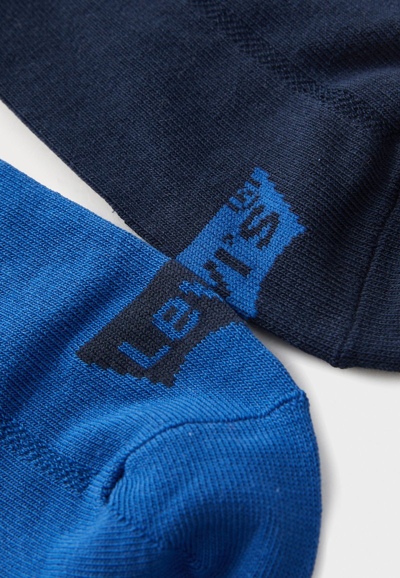 Dos pares de calcetines: uno en color marino y otro en azul brillante, ambos con una textura suave y un logo negro de 'Levi’s' en el calcetín azul.