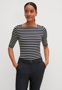 Haut ajusté à rayures avec des rayures horizontales bleu marine et blanches ; présente un col bateau et des manches courtes ; associé à un pantalon sombre.