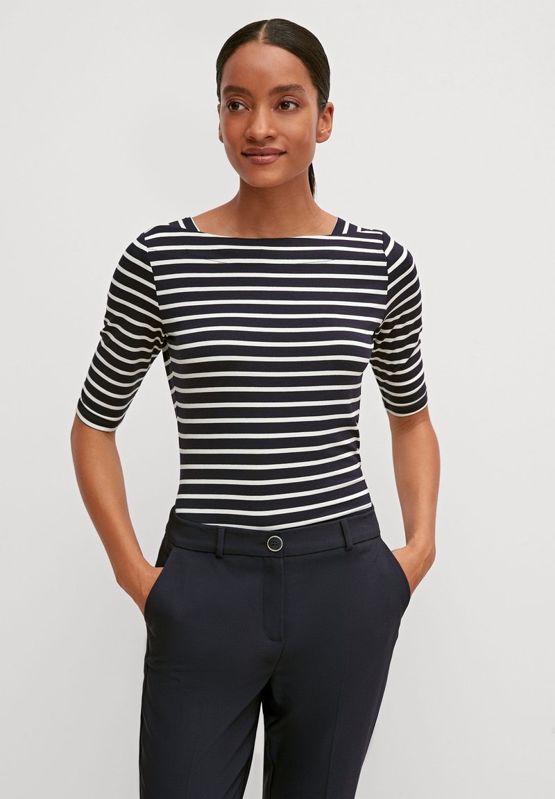 Haut ajusté à rayures avec des rayures horizontales bleu marine et blanches ; présente un col bateau et des manches courtes ; associé à un pantalon sombre.