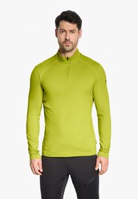 Langärmliges Sportshirt in leuchtendem Limettengrün, mit hohem Kragen und halbquem Reißverschluss. Hergestellt aus glattem, dehnbarem Stoff.