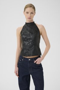 Svart skinn halterneck-top med en teksturert overflate og front-søm detaljer, kombinert med mørkeblå, høy-midje denimjeans.