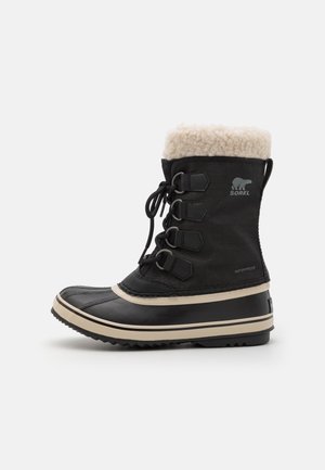 Schwarzer wasserdichter Stiefel mit einem Kunstfellkragen, Schnürverschluss, Gummisohle und kontrastierendem beigem Streifen entlang der Sohle. Dekorative Hardware-Details.
