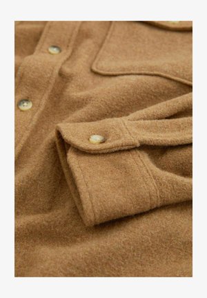 Braunes Wollhemd mit weichem Textil, ausgestattet mit einer durchgehenden Knopfleiste, einer Brusttasche und abgerundeten Manschetten mit hornähnlichen Knöpfen.