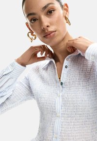 Siniste triipudega, tekstuuriga nööbitav särk kraega kaelusega. Omaduseks pärlnööbid ja roheline aktsendinööp. Pikad varrukad mansettidega.