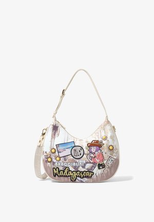 Sac à bandoulière blanc avec des patchs sur le thème du voyage, comprenant "Braccialini Madagascar", une fille dessinée avec un appareil photo, un lémurien et des images de paysages.