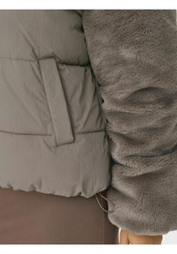 Gray puffer jacket with a plush, faux fur sleeve contrast. Features a side pocket and a cinched waist for a snug fit. Textured fabric visible.