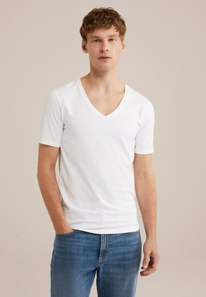 Hvid bomulds kortærmet V-hals t-shirt, tætsiddende design, glat tekstur, parret med blå denim jeans, stående foran en neutral baggrund.