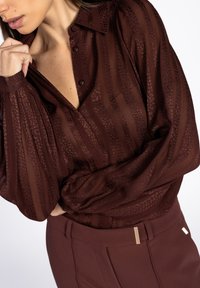 Bordeaux doorschijnende blouse met gestreepte textuur en knopenlijst, met pofmouwen en gecombineerd met hoge taille bijpassende broeken.