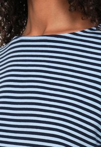 Navy and light blue striped fabric with a smooth texture, featuring a relaxed neckline and fitted sleeves. Patterns are evenly spaced.