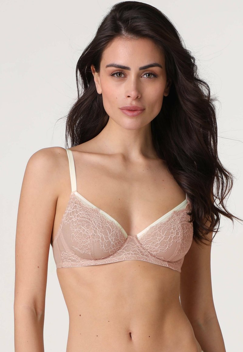 Reggiseno triangolare in pizzo colore nudo con spalline avorio, caratterizzato da motivi floreali, texture morbida e dettaglio con scollo a V.