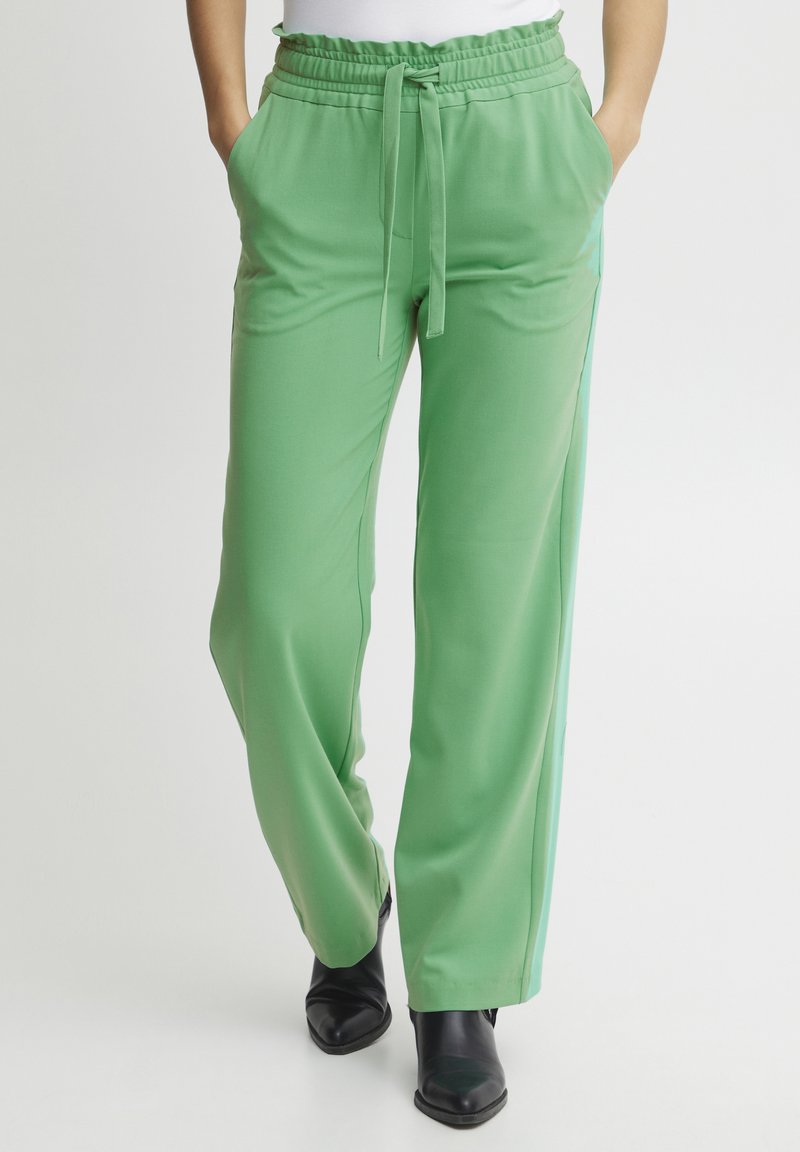 Green wide-leg pants with an elastic waistband and tie detail, featuring two side pockets and a smooth, lightweight fabric.