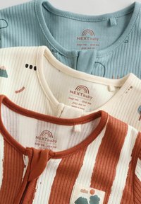 Kolm voltinud beebikeha, mis on roostevärvi valgete triipudega, kreem värvi abstraktsete trükkidega ja ühetooniline tuhksinine peente mustritega.