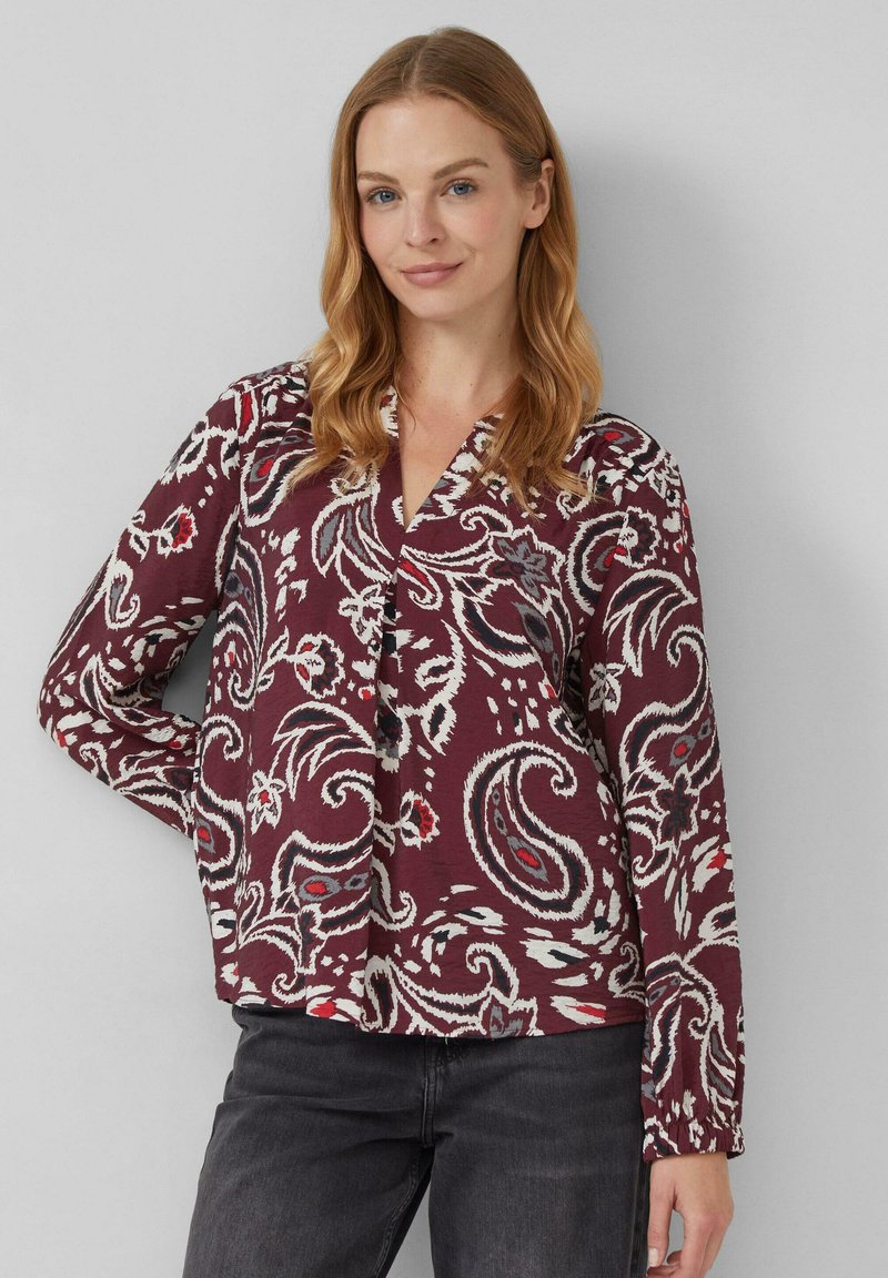 Langärmlige Bluse in einem tiefen Burgunderrot mit einem floralen Paisleymuster in Weiß, Rot und Blau. Mit V-Ausschnitt und gerafften Bündchen.