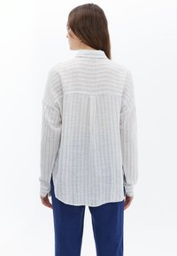 Witte en blauwe gestreepte langemouwen shirt met een iets losse pasvorm, voorzien van een achterpleat, klassieke kraag en afgeronde zoom.
