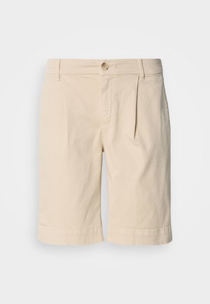 Beige Baumwollshorts mit geradem Schnitt, ausgestattet mit einem umgeschlagenen Saum und einem einzelnen Knopfverschluss. Entworfen mit vorderen Falten und seitlichen Taschen.