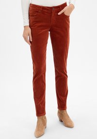 Rdzawoczerwone spodnie z korduroy o slim fit, z przednimi kieszeniami i guzikiem w talii. Miękka tekstura i tapered leg design.
