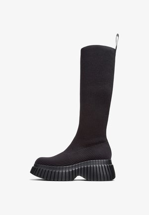 Czarne dzianinowe kozaki za kolano z prążkowaną fakturą, wyposażone w grubą, żłobioną podeszwę zapewniającą lepszą przyczepność i stabilność.