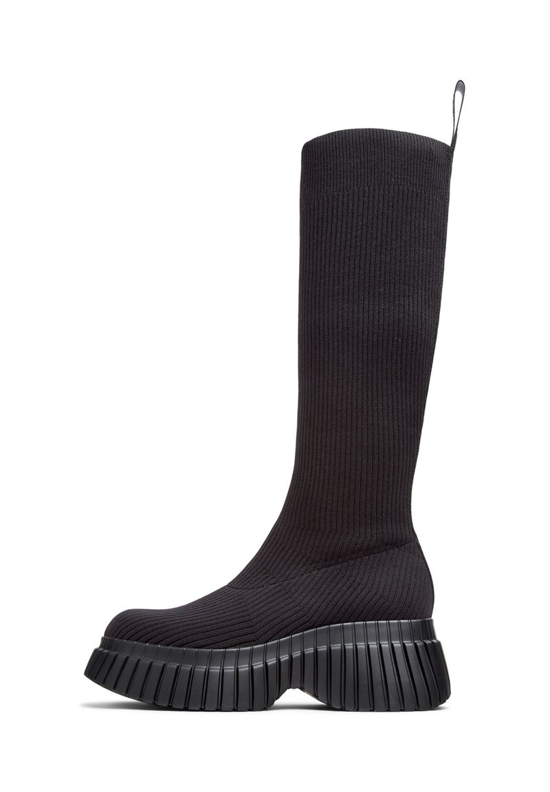 Botas negras de punto hasta la rodilla con textura acanalada, que cuentan con una suela gruesa y estriada para mayor agarre y estabilidad.