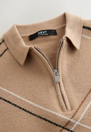 Beige Strickpullover mit Kragen, halbem Reißverschluss und kontrastierenden diagonalen Streifen in Schwarz und Weiß. Weicher Stoff. Markenlabel: NEXT.