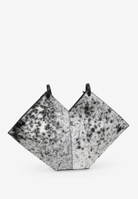 Bolso de piel de vaca en blanco y negro con un diseño geométrico, con una textura suave, dos asas circulares y un patrón moteado distintivo.