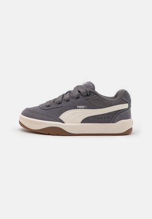 Grey suede sneaker with beige accents, featuring a rubber sole, lace-up closure, and side logo detail. Low-top design with textured surface.