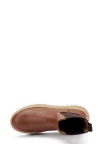 Botín de cuero marrón hasta el tobillo con punta redonda, panel lateral elástico y suela de goma texturizada. Incluye una lengüeta para facilitar el uso.