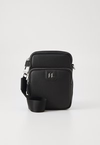 Sac porté travers noir en synthétique avec une finition texturée, des fermetures éclair argentées, une sangle ajustable et un logo en relief à l'avant.