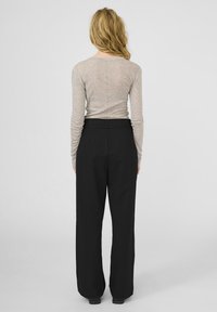 Lichtgrijze langemouwen top gecombineerd met hooggewaardeerde zwarte wijde broek. Gladde texturen, minimalistisch ontwerp, geen zichtbare patronen of accenten.