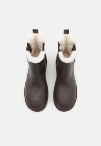 Botas de tobillo marrones con una superficie texturizada y un patrón de diamantes, forro de forro polar en la parte superior y una pestaña para facilitar el uso.