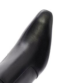Scarpa in pelle nera con punta affilata, texture liscia e design minimalista. Presenta una silhouette elegante e senza hardware visibile.