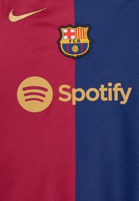 Maglia del FC Barcelona, caratterizzata da un design diviso con sezioni rosse e blu, logo Nike dorato, stemma del club e branding Spotify.