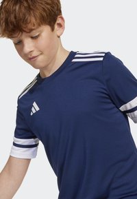 T-shirt de sport bleu marine en tissu léger avec des rayures blanches sur les manches et un logo iconique sur la poitrine. Manches courtes et col rond.