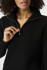 Pull en tricot noir côtelé avec un col haut et une fermeture éclair dorée. Présente une ouverture zippée sur le quart et un tissu texturé pour la chaleur.