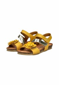 Sandalias amarillas con detalles metálicos plateados y una flor en la punta. Cuentan con correas ajustables y una suela de corcho texturizada.
