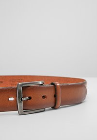 Cinturón de cuero marrón con una textura suave, que presenta una hebilla de metal plateado y múltiples agujeros de ajuste para un mejor calce.