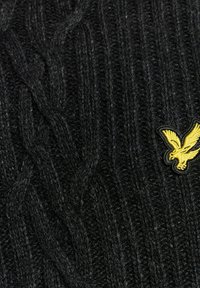 Suéter negro de punto con un patrón de cable y un pequeño logo de águila amarilla en el pecho. Tela texturizada con detalles acanalados.