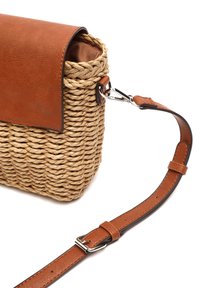 Borsa di paglia intrecciata con una patta e tracolla in pelle marrone. Presenta una chiusura in metallo, una superficie texture e una morbida fodera interna in tessuto.