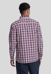 Camicia a quadri nei toni di viola, rosa e nero. Presenta maniche lunghe, colletto classico e un orlo dritto.