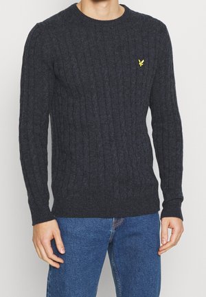 Tmavě šedý svetr s kabelovým vzorem, dlouhými rukávy, kulatým výstřihem a malým žlutým logem na levé straně hrudi. Měkká textura.